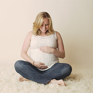 Expectant mom sitting holding her belly sitting maternity pose