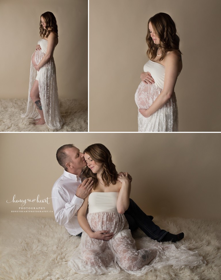 Expecting mom posing in studio long white cream lace gown sitting with dad soft romantic couples pose calgary maternity photographers maternity & pregnancy pictures 