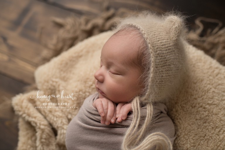 Baby Boy swaddled in newborn photography wrap with hands peeking out wearing angora knitted bonnet - neutral and earth tones calgary baby pictures