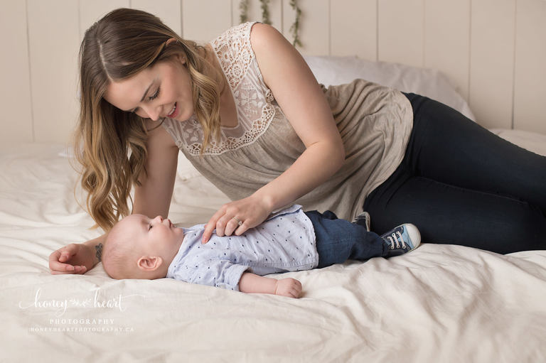Baby laying on bed and mom interacting with baby studio photography session baby photographers Calgary AB